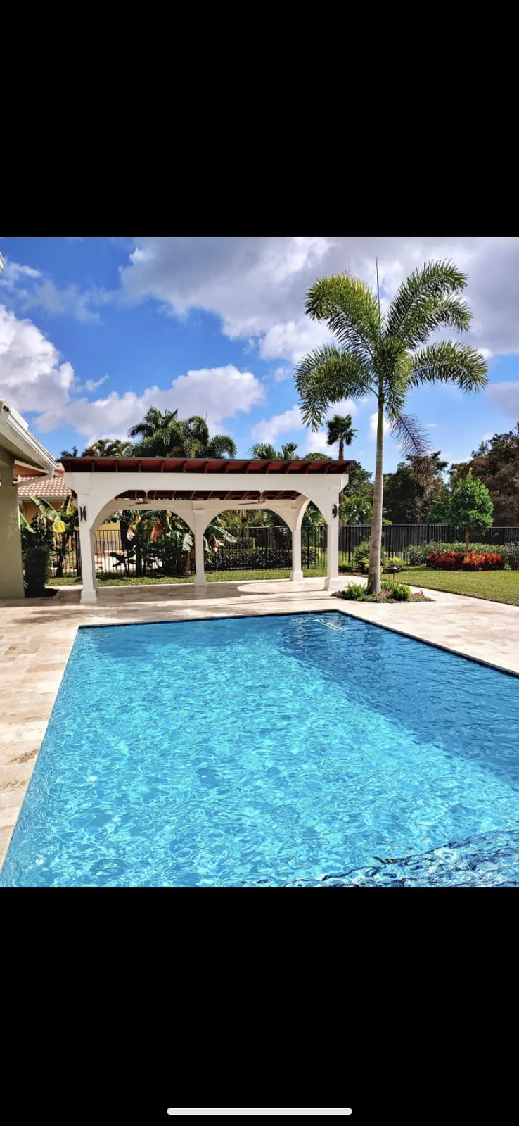 Resort-style backyard with sparkling pool, white pergola, and manicured landscaping.