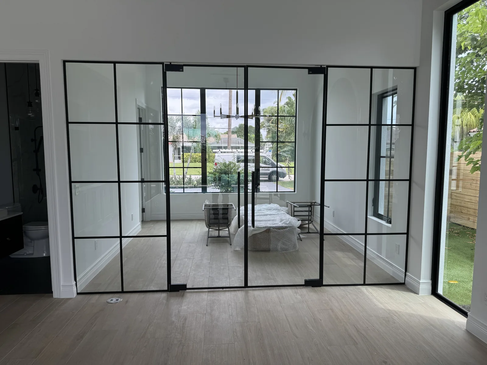 Glass partition doors with black steel frames between bedroom and living space.