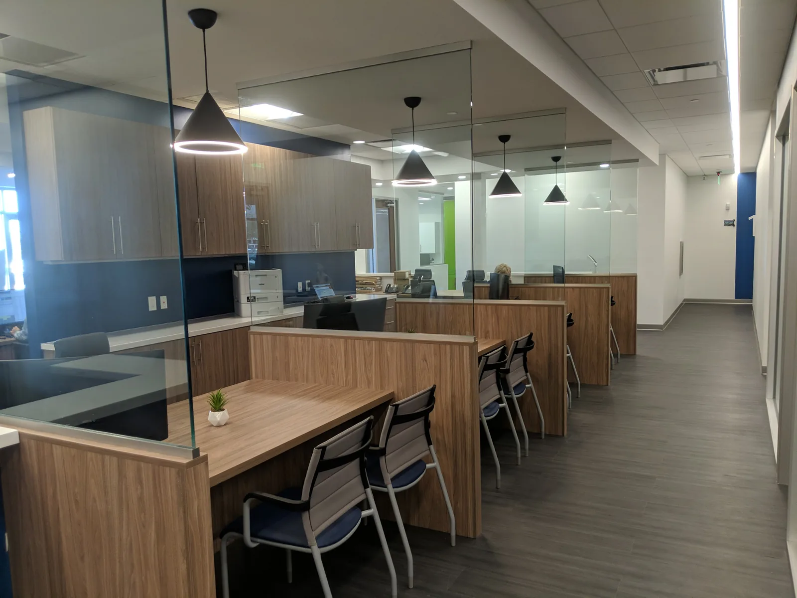 Office workstations with wood-grain finish and glass partitions during build-out.