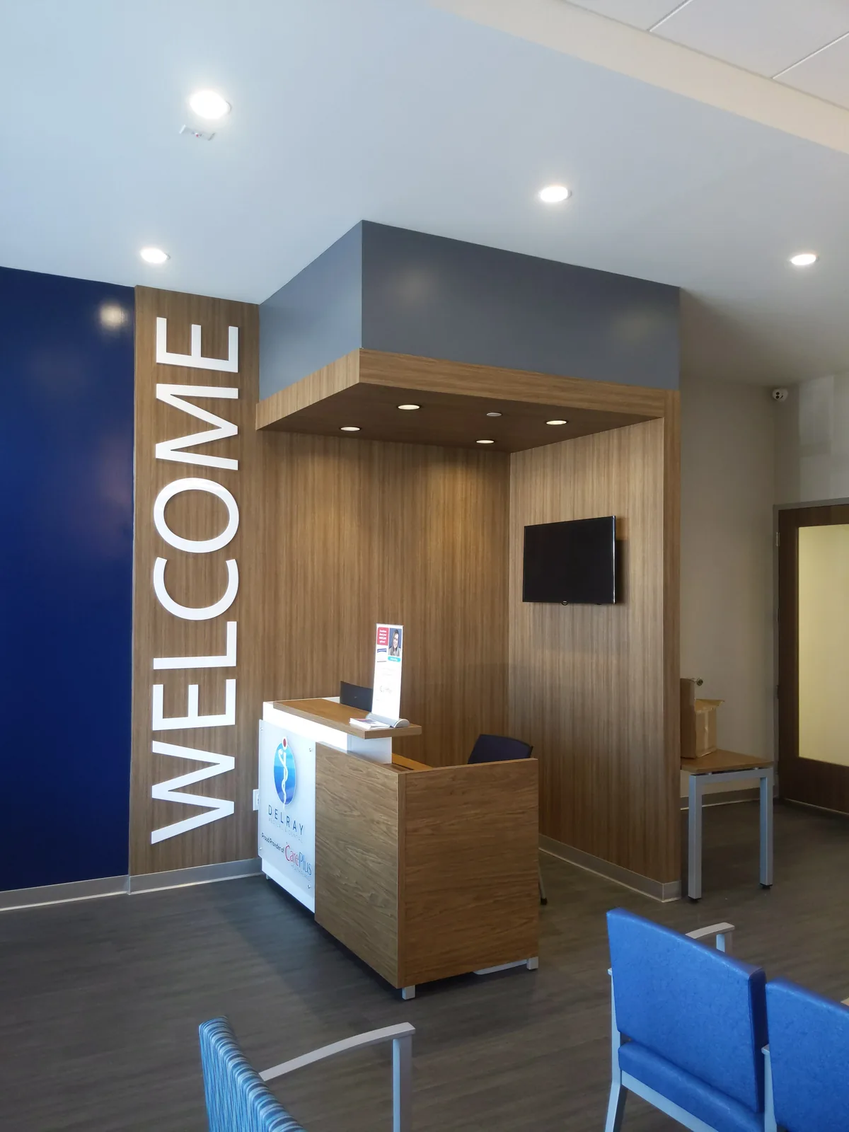 Medical office reception with welcome desk, wood paneling, blue accent wall.