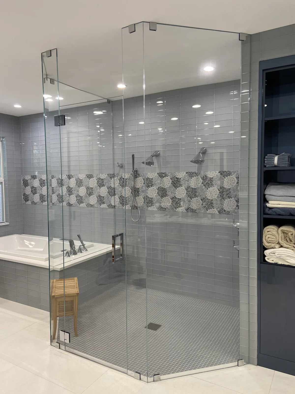 Spa-style walk-in shower with frameless glass enclosure and decorative tile accents.