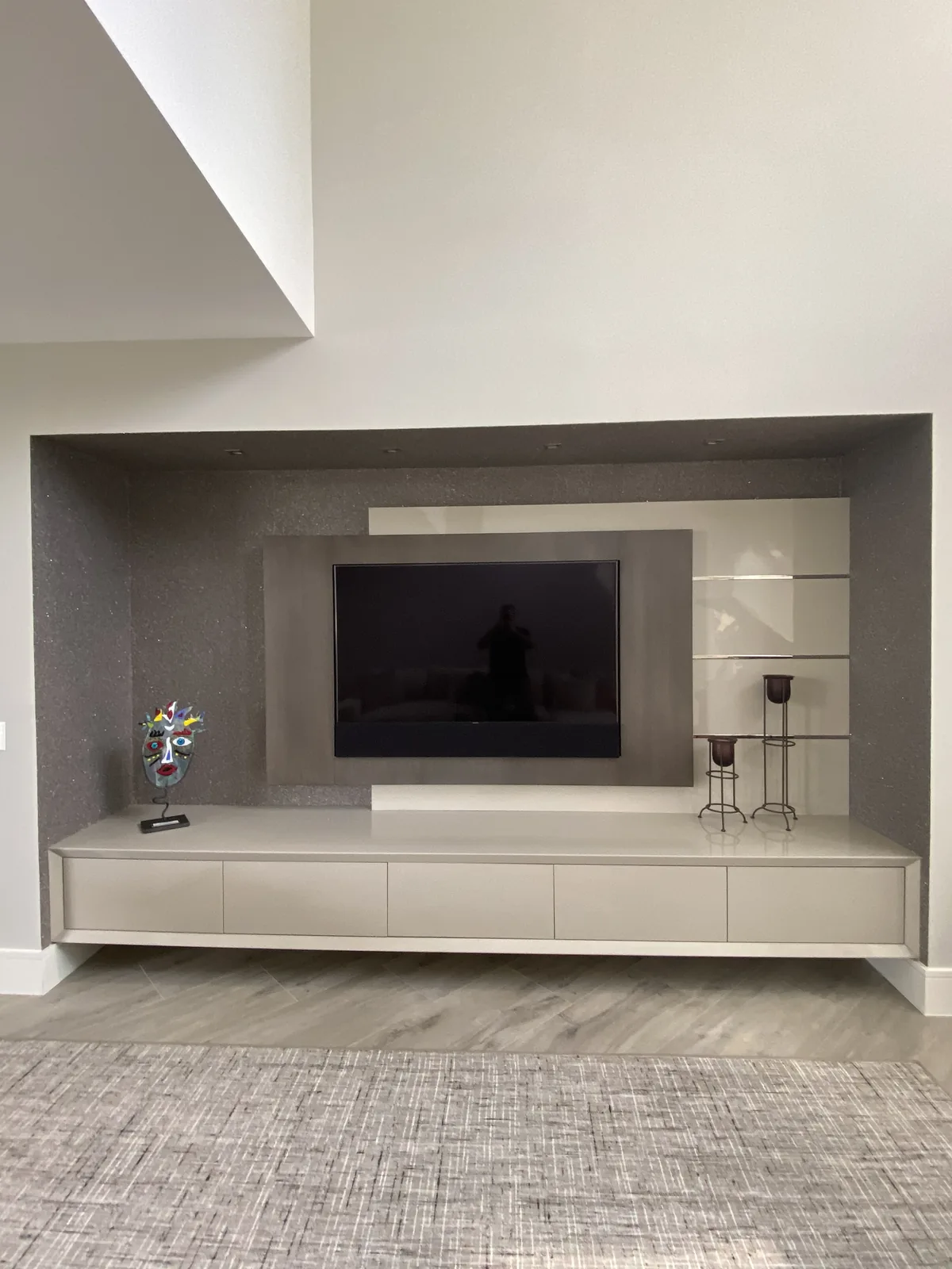 Media wall with integrated flat-screen, white cabinetry, and decorative shelving.