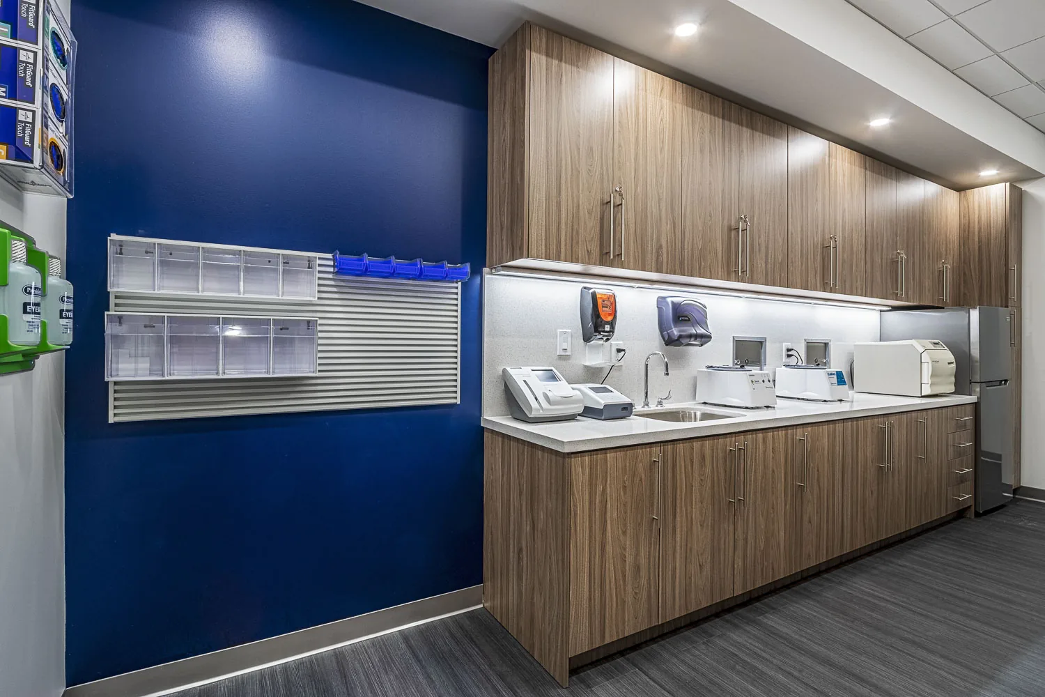Medical clinic interior with blue accent wall, wood cabinetry, and clinical equipment.