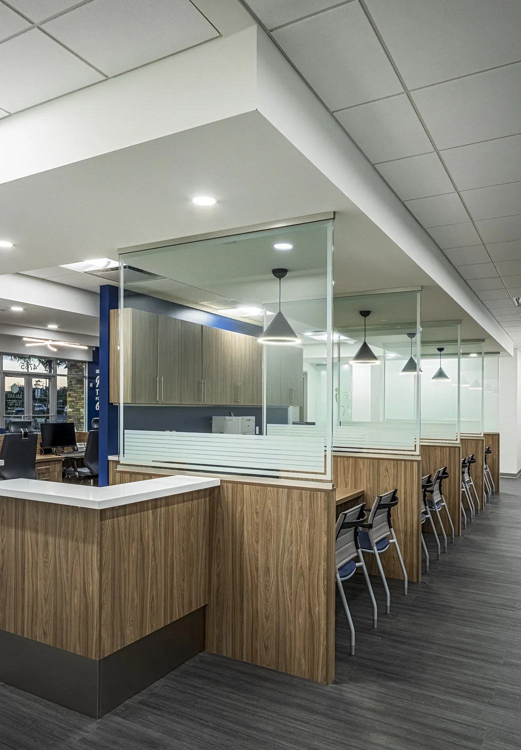 Commercial office with wood and glass partitions, pendants, and reception counter.