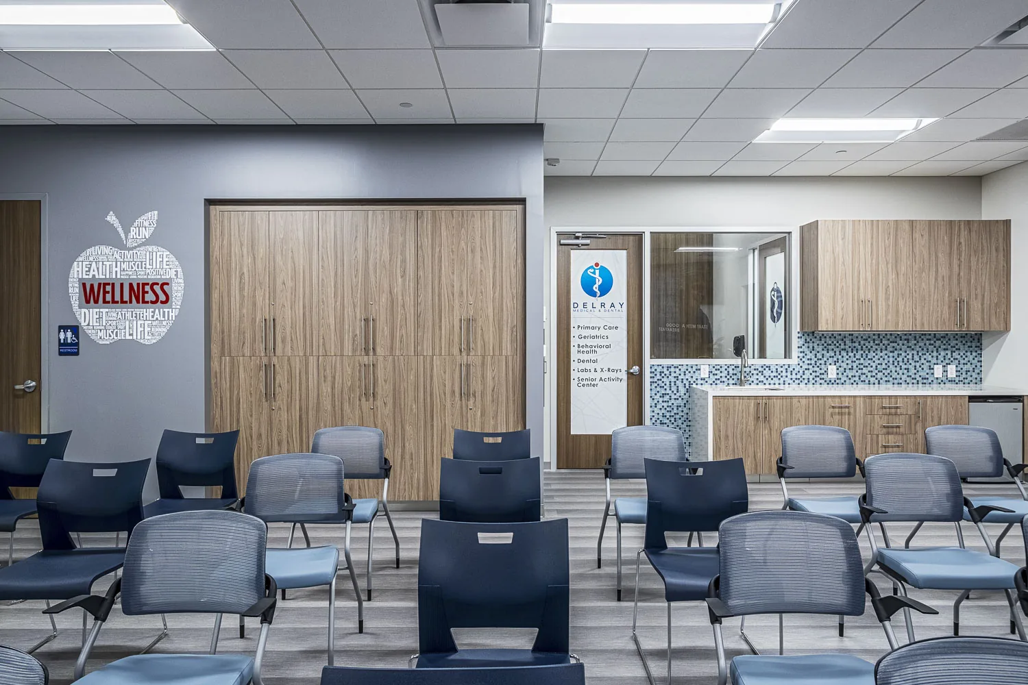 Medical clinic waiting room with wood cabinetry and wellness wall graphics.