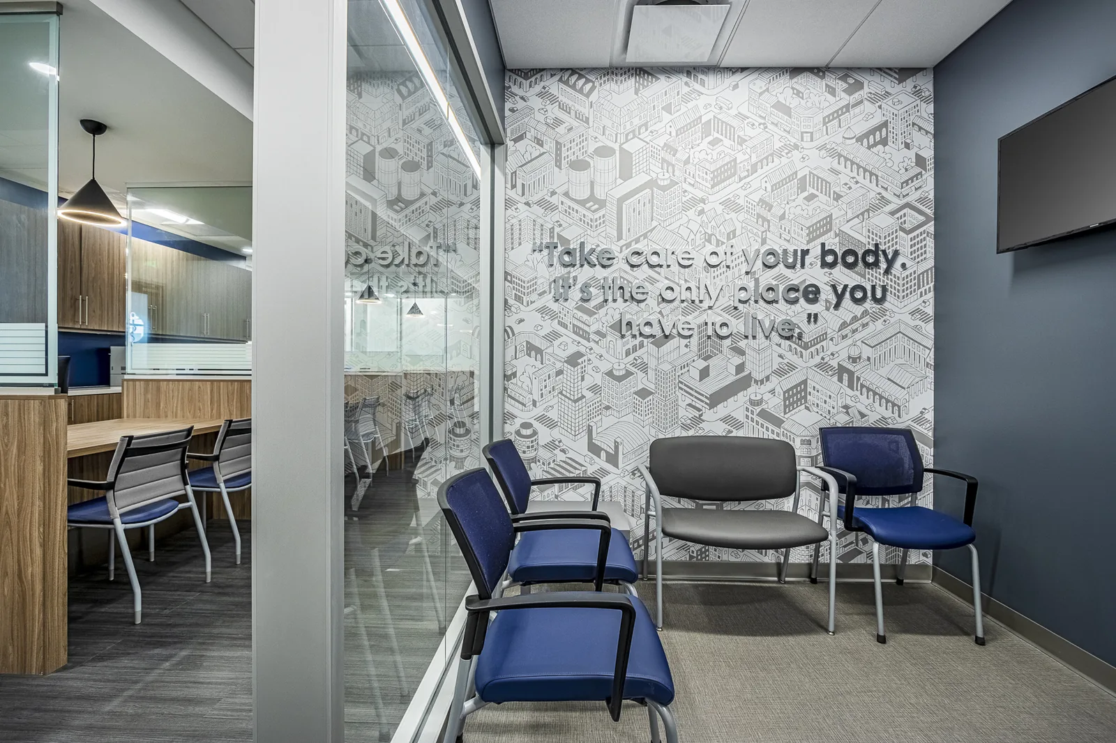 Medical waiting room with blue and black chairs and isometric city wallpaper.