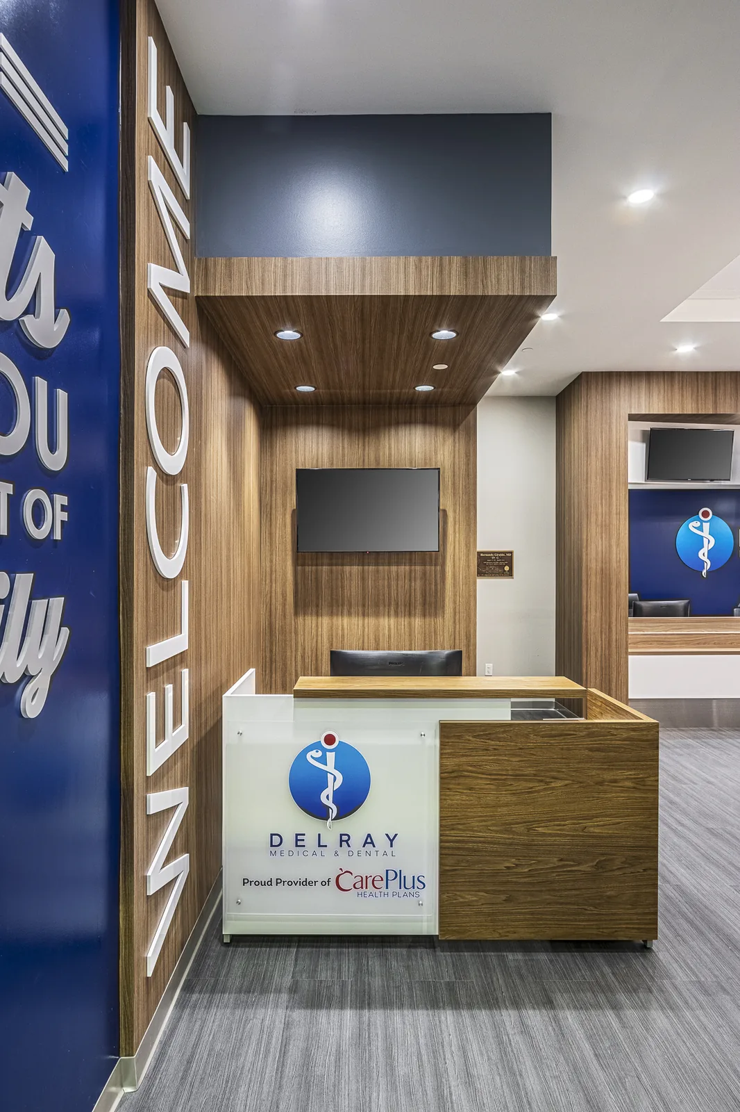 Medical office reception with wood paneling and branded blue signage.